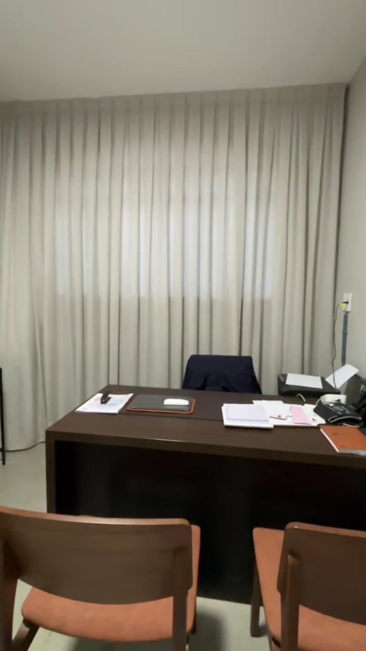 Escritório com cortina clara atrás da mesa