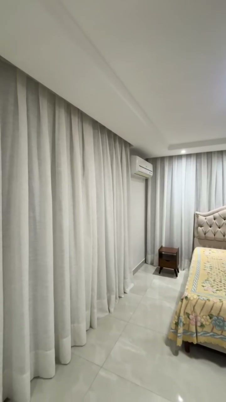 Quarto com cortina de linho clara cobrindo a parede, vista pelo corredor
