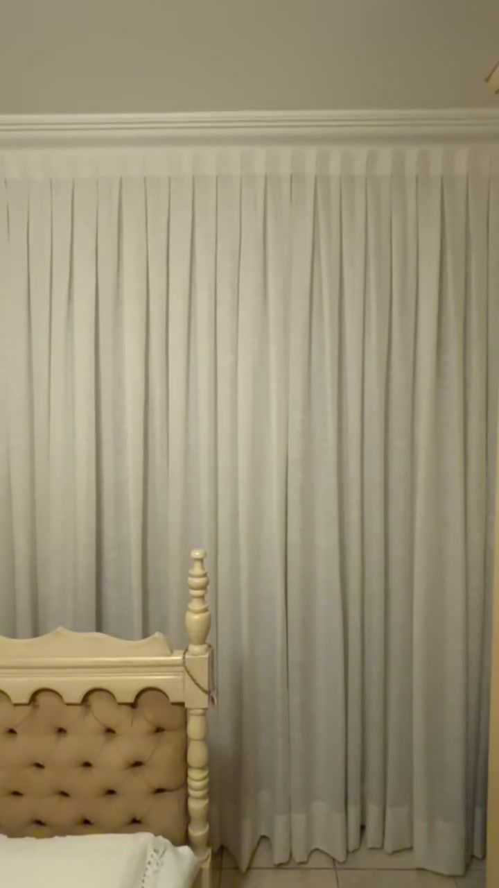 Quarto com cortina bege e cama de cabeceira clássica