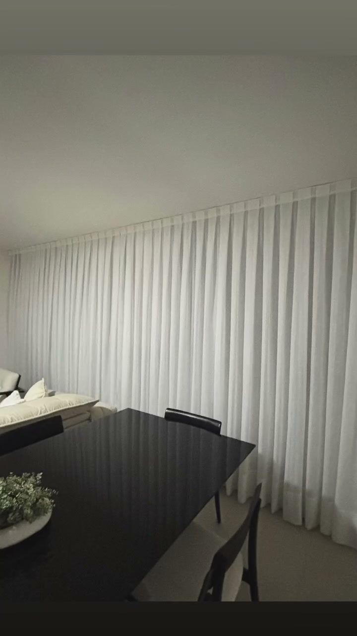 Sala de jantar ampla com cortina clara do teto ao chão