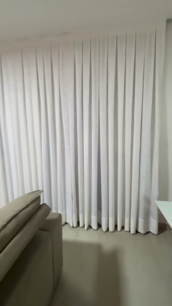 Cortina de linho claro cobrindo a parede inteira de uma sala