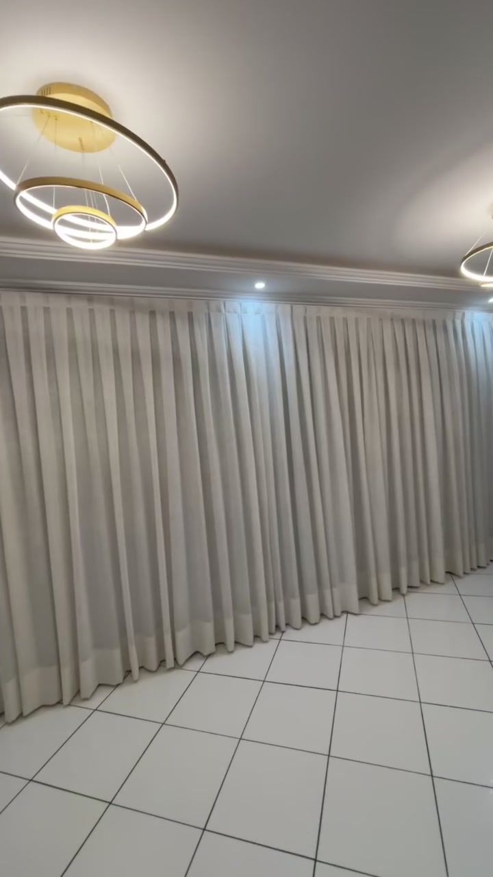 Sala de pé-direito alto com cortina de linho em toda a extensão